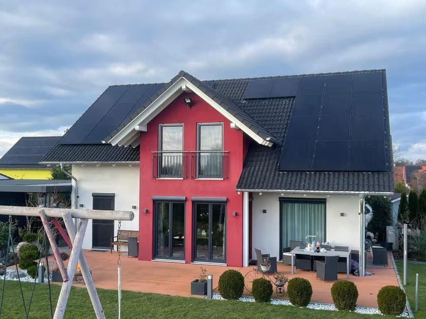 Rotes Haus mit Photovoltaik auf dem Dach