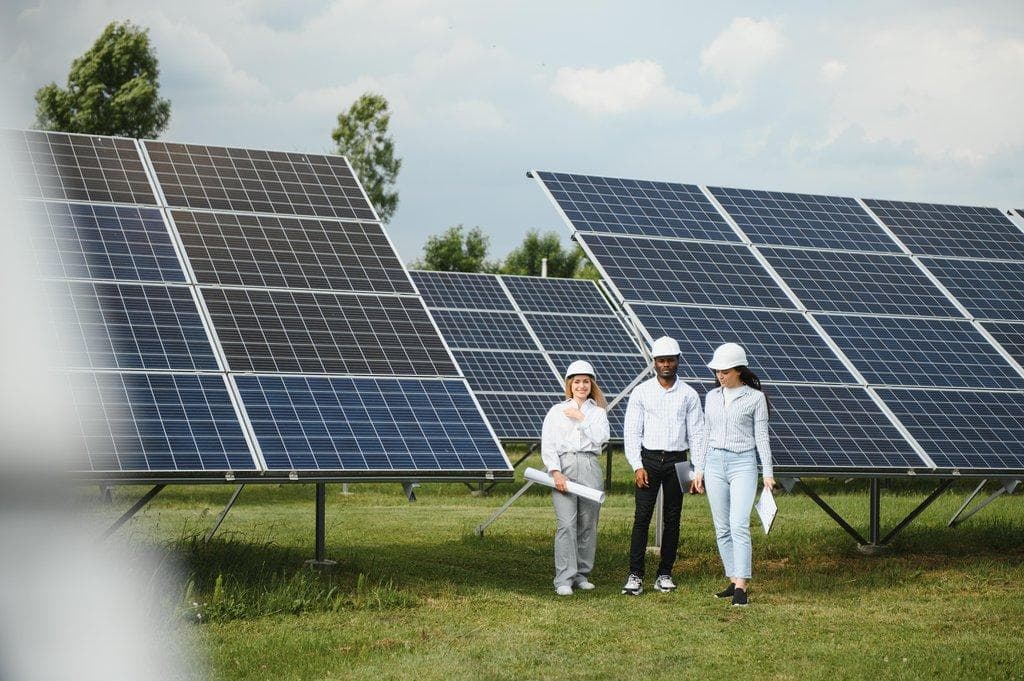 Team von Ingenieuren steht draußen neben Solarmodulen
