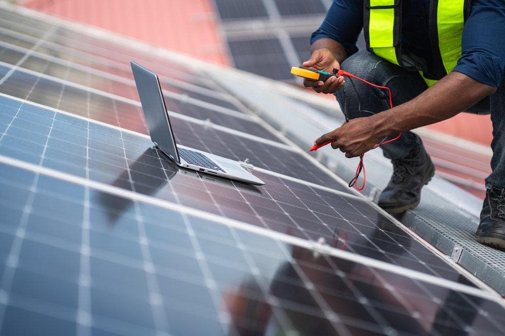 Service-Ingenieur prüft Solarzelle auf Dach mit Multimeter